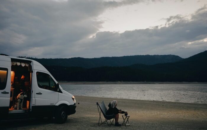 New vs Used Motorhome - Woman and Dog sitting by a lake