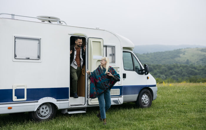 A couple in their 30s steps out of their camper van, waking up to the beauty of nature.